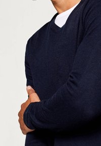 Navy blue, V-neck sweater made of soft fabric. Features long sleeves and a fitted design, with a smooth texture and no visible patterns.