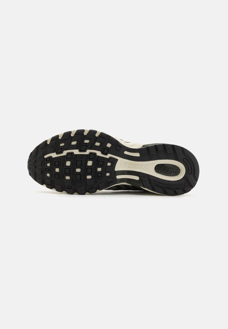 Schwarzer und cremefarbener Sneaker-Außensohle aus strukturiertem Gummi, mit unterschiedlichen quadratischen Mustern und erhöhten Stollen für Traktion, beschriftet mit "AIR PEGASUS."