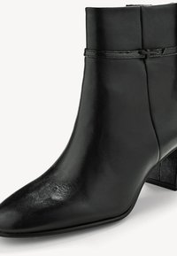 Bottine noire en cuir avec un petit talon carré et une fine bride autour de la tige supérieure.