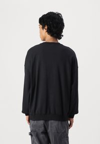 Black sweatshirt with a relaxed fit, crew neck, and long sleeves. Soft fabric and ribbed cuffs at the hem and sleeves.