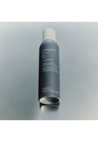 Living Proof Perfect Hair Day Trockenshampoo-Dose, marineblau mit weißem Deckel, auf reflektierender grauer Oberfläche, Text mit Produktvorteilen sichtbar.