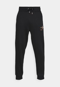 Zwarte trainingsbroek van zacht materiaal. Voorzien van een trekkoord in de taille, geribbelde boorden en een klein gouden geborduurd logo op de voorkant.