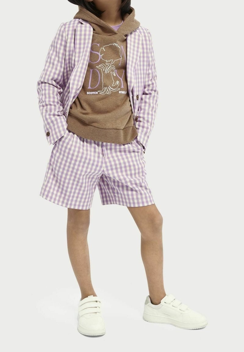 Lila och vit rutmönstrad kavaj, matchande shorts, brun hoodie med grafisk design, och vita sneakers med kardborreband.
