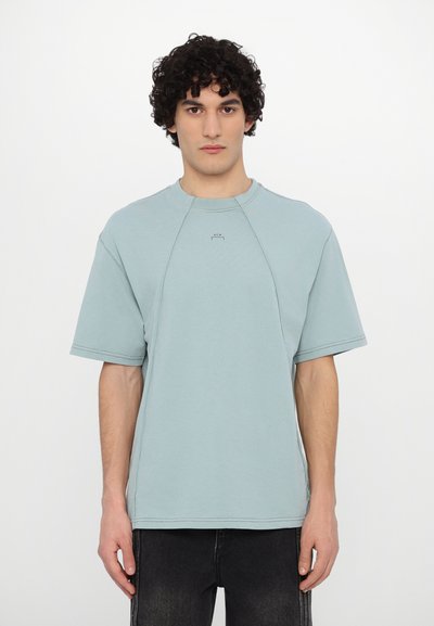Tricou oversized de culoare albastru deschis, cu mâneci scurte, guler rotund, cu cusături vizibile și un detaliu mic cu logo pe față.
