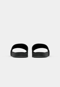 Black slide sandals with an open-back design, made of smooth material. Features a contoured footbed and minimalistic, rounded accents.