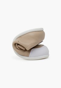 Scarpe in pelle morbida di colore beige e bianco con suola flessibile, caratterizzate da una superficie testurizzata e un design minimalista, piegate per occupare meno spazio.