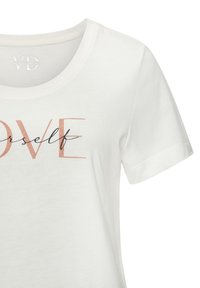 Baumwoll-T-Shirt in Creme mit Rundhalsausschnitt. Auf der Vorderseite steht das Wort "LOVE" in Koralle und "yourself" in schwarzer Schreibschrift. Kurze Ärmel.