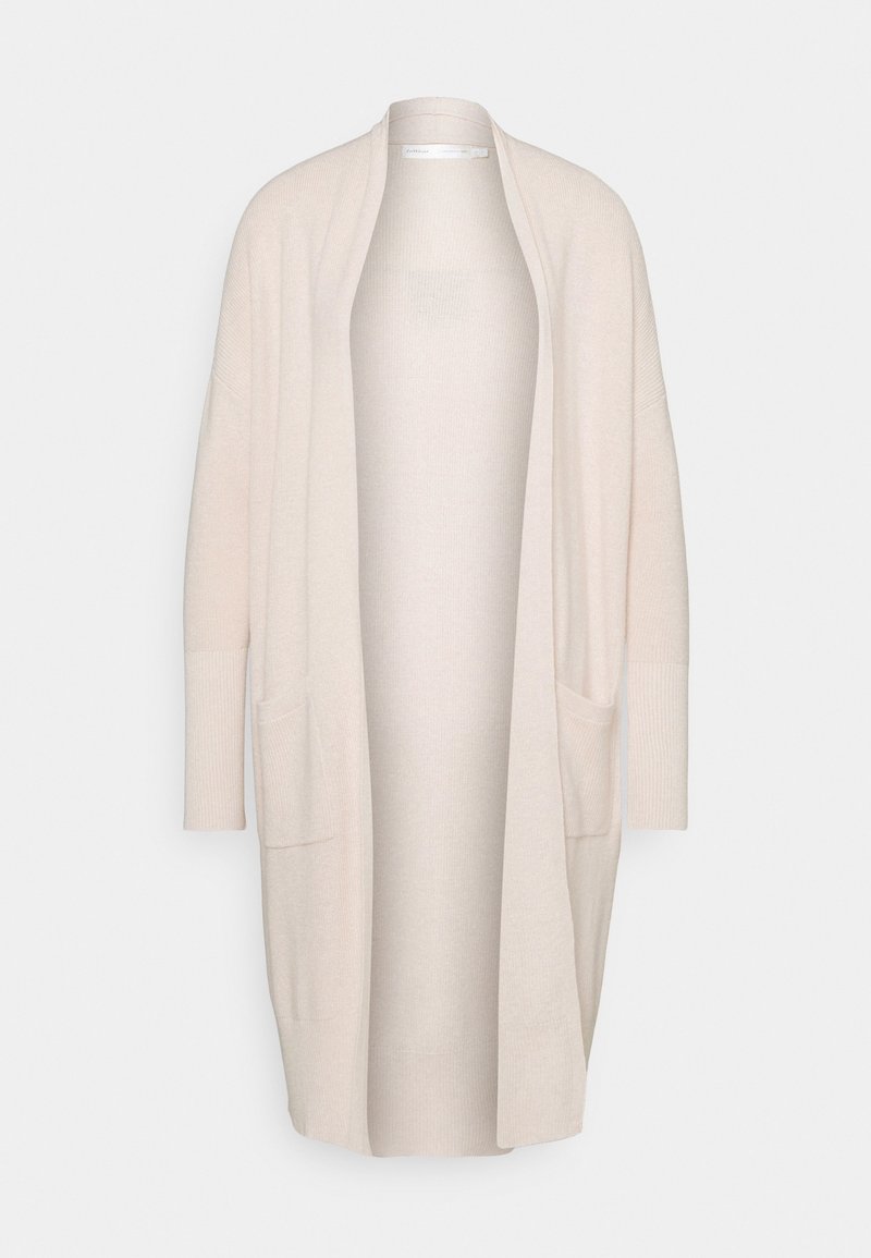 Cardigan beige long et doux, à l'avant ouvert, avec deux poches frontales et des poignets côtelés, présenté sur un fond blanc uni.
