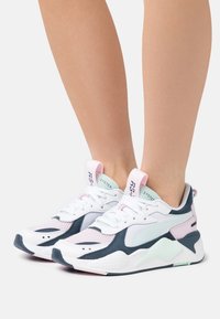 Białe i granatowe buty sportowe z panelami z siateczki, pastelowo różowymi akcentami, zaokrąglonym noskiem, grubą gumową podeszwą i pewnym systemem sznurowania.