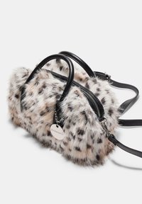 Borsa in finta pelliccia con stampa leopardata, manici in pelle nera, chiusura con zip, tracolla staccabile e etichetta del marchio in argento su sfondo bianco.