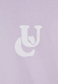 Fialová bavlněná látka s velkým bílým logem, složen�ým ze stylizovaných písmen "U" a "C", s hladkou texturou.