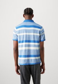 Polo a righe nei toni di blu e bianco, realizzato in morbido cotone. Presenta un colletto classico e maniche corte, con righe orizzontali regolari.