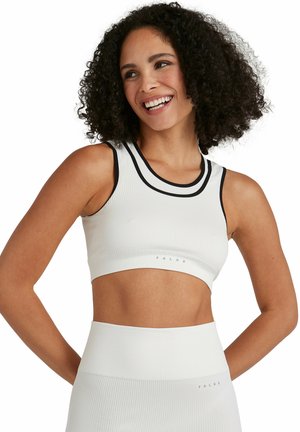 Crop top de sport blanc avec texture côtelée, accents noirs au niveau du col et logo en bas. Design ajusté pour les vêtements de sport.