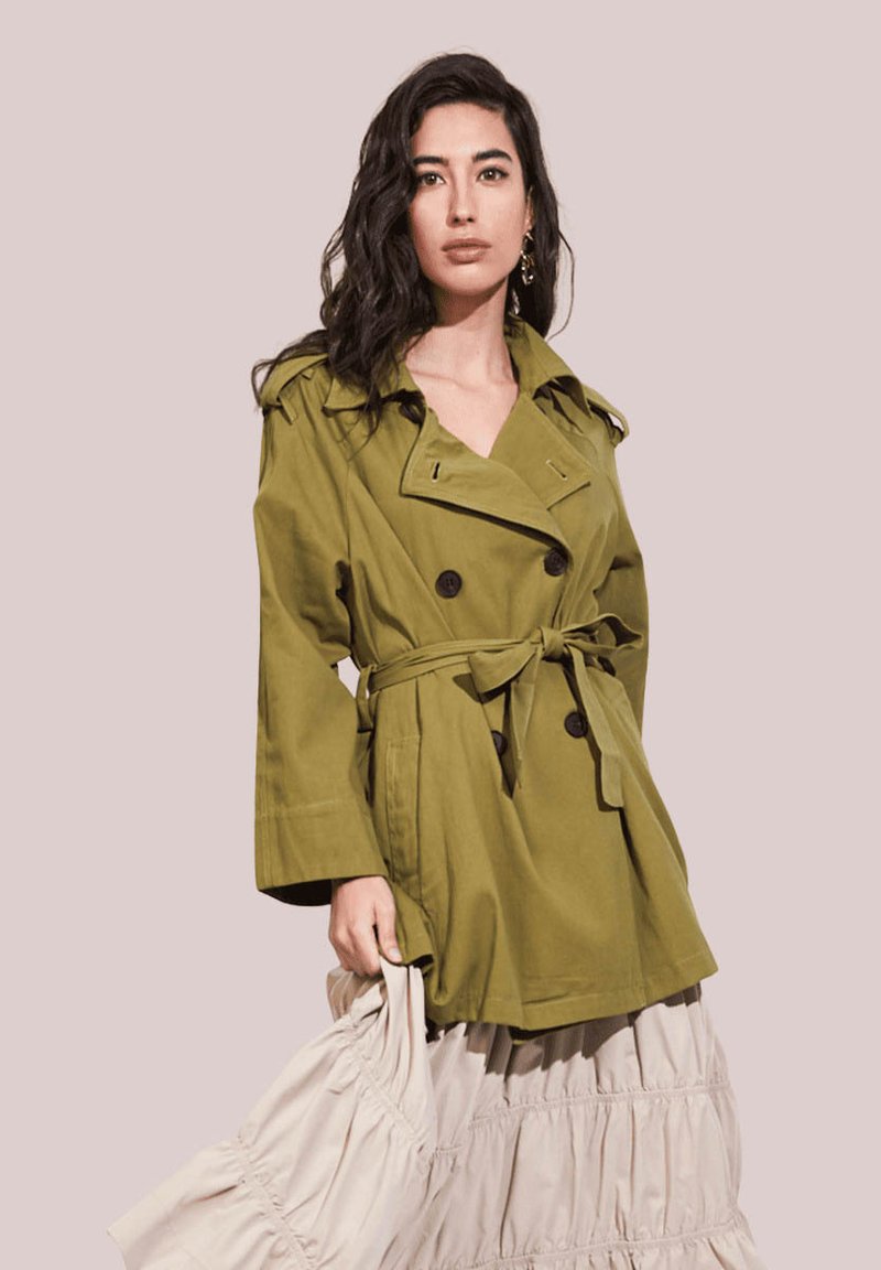 Trench coat verde oliva con botones de doble botonadura, amplias solapas y cinturón en la cintura. Tela texturizada con bolsillos laterales; diseño ligero.
