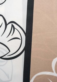 Látka s plynulými květinovými vzory v černé a bílé na béžovém pozadí s texturovanými detaily. Viditelné abstraktní designové prvky.