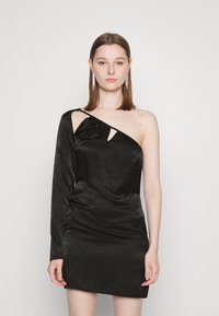 Vestido preto de uma só shoulder com tecido texturizado, apresentando um lado franzido, detalhe recortado e uma silhueta ajustada. Design até ao joelho.