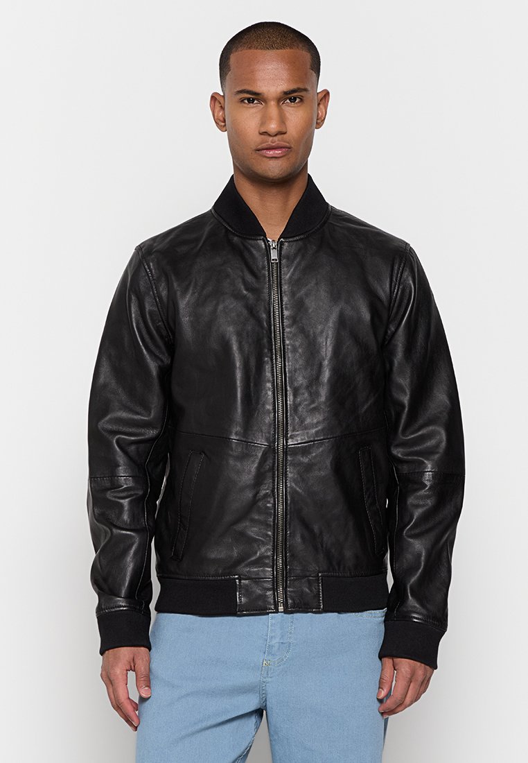 Giubbotto bomber in pelle nera con polsini e colletto a costine, chiusura con zip e tasche laterali. Texture liscia e design aderente.