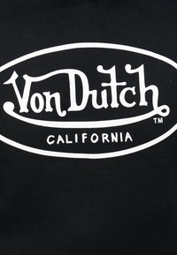 Von Dutch-Logo in stilisiertem weißem Text innerhalb eines Ovals mit der Aufschrift "California" darunter, vor schwarzem Hintergrund.