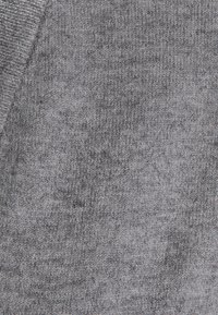 Tissu tricoté gris avec une surface douce et texturée. Les variations de couleur créent un motif subtil, idéal pour les vêtements décontractés ou les accessoires.