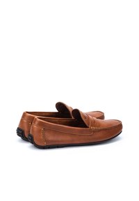 Mocasines de cuero marrón con punta redonda, detalles de costura y suela de goma flexible. La parte superior presenta una correa decorativa.