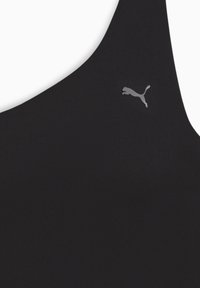 Zwarte sportbeha van een gladde, elastische stof met een subtiele glans. Een klein grijs Puma-logo bevindt zich aan de linkerkant.