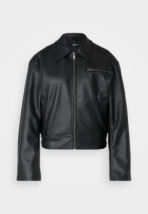 Must lille mustade nahkjope, mis on lühikesed, esiluku, laia krae ja ühe tõmblukuga rinnakotiga. Sile tekstuur minimaalse detailiga.