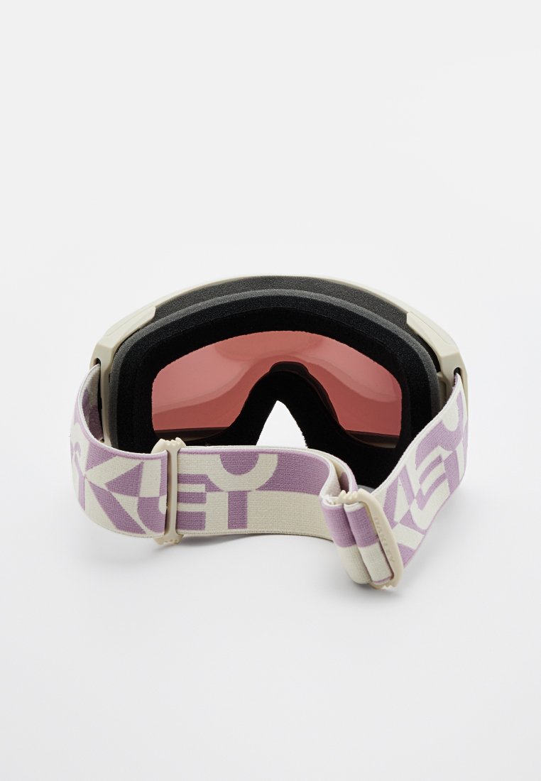 Skibrille mit rosa Linse, schwarzem Schaumstoffpolster und breitem Band mit lila geometrischen Mustern. Kompaktes, unauffälliges Design.