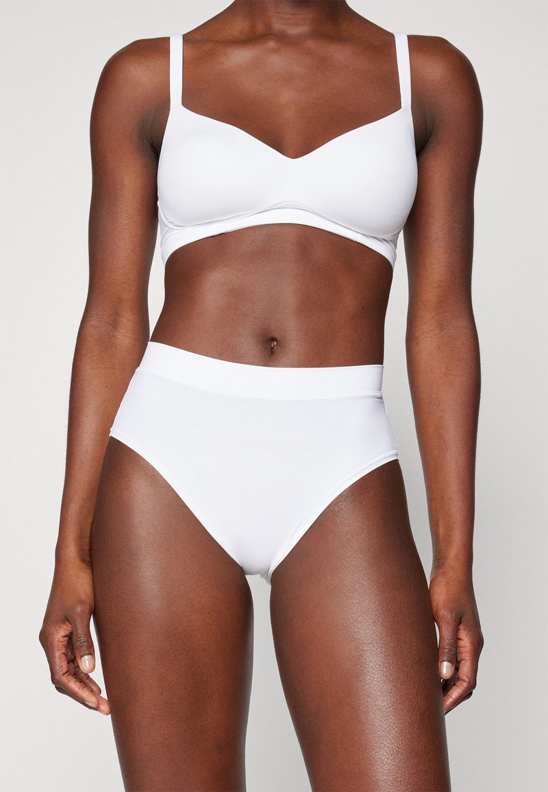 White seamless bralette with adjustable straps and a V-neckline, paired with high-waisted white briefs, both made from smooth fabric.