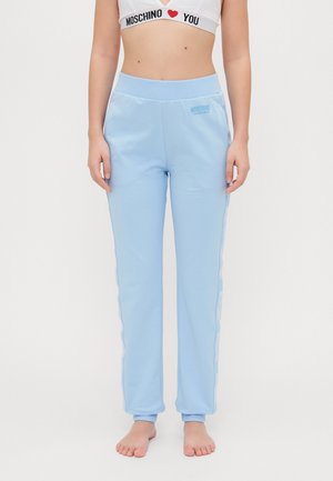Light blue athletic pants with a smooth texture, elastic waistband, and white logo detailing along the sides. Fitted at the ankles.