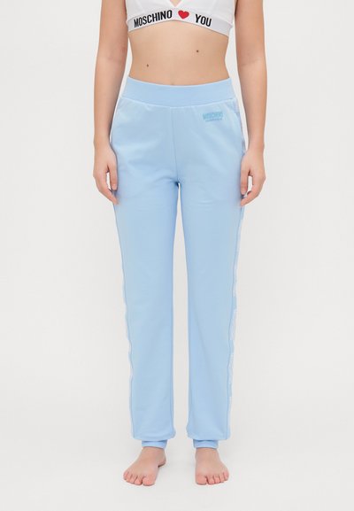 Pantaloni sportivi de culoare albastru deschis, cu o textură netedă, talie elastică și detalii cu logo alb pe părțile laterale. Ajustați la glezne.