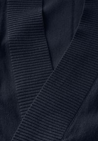 Tissu tricoté bleu marine avec des bords côtelés, présentant une texture lisse et un design en V, affichant des teintes sombres superposées et des lignes épurées.