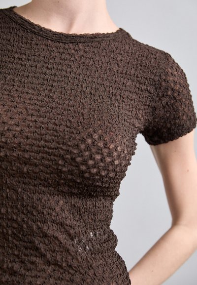 Hnědý pletený top s texturovaným, vyvýšeným vzorem. Krátké rukávy a kulatý výstřih, přičemž má přiléhavý střih a mírnou průhlednost.