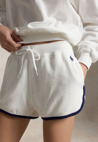 Λευκά σορτς από πετσετέ ύφασμα με κορδόνι, με μπλε επένδυση και κεντημένο λογότυπο, φορεμένα με λευκή μακρυμάνικη μπλούζα που ταιριάζει.