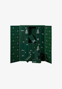 Calendrier de l'Avent vert avec 24 cases, chacune portant un numéro. Présente un texte blanc et des motifs d'arbres. S'ouvre pour révéler des cadeaux à l'intérieur.