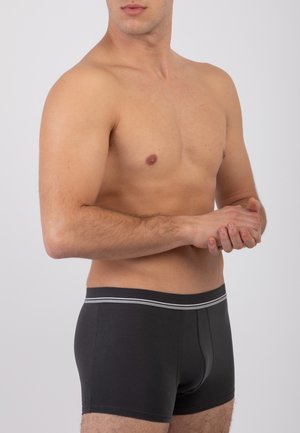 Boxer da uomo neri con un design aderente, dotati di una cintura elastica grigia e una trama di tessuto liscia. Il modello è posato di profilo.