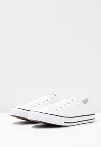 Weiße Leinenschuhe mit schwarzen Streifen an der Sohle, runde Zehenpartie, sechs Ösen und flachen Schnürsenkeln, ausgestattet mit einer strukturierten Gummisohle.