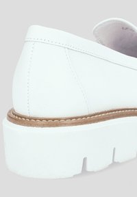 Białe skórzane buty wsuwane z zaokrąglonym czubkiem, białą platformą i brązowym przeszyciem wzdłuż podstawy dla dodatkowego kontrastu.