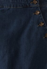 Mörkblå denimkjol med knälång skärning, fem knäppningar på sidan och subtil textur med svaga vertikala linjer.