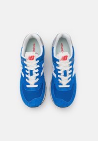 Blå mocka- och nätaktiga skor med vita detaljer, som har en vadderad krage, snörning och en framträdande logotyp på tungan.