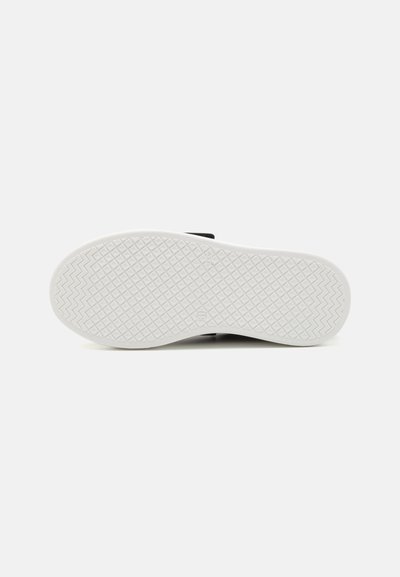 Suela de zapato negra con una parte inferior blanca texturizada que presenta un patrón de diamantes y zigzags para agarre. Diseño plano.