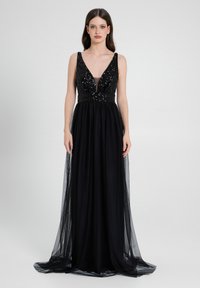 Schwarzes Abendkleid mit tiefem V-Ausschnitt, glitzerndem Oberteil und fließendem, transparentem Rock. Besitzt eine taillierte Passform und verstellbare Träger.