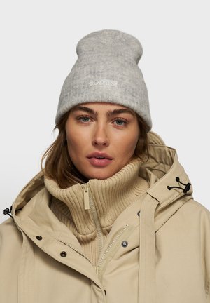 Berretto grigio lavorato a maglia con orlo arrotolato e testo ricamato. Giacca beige con zip, colletto alto e strato interno in maglia a costine.
