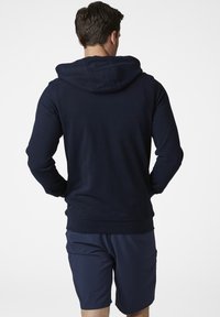 Sudadera azul marino con capucha ajustable, mangas largas y una textura suave, combinada con pantalones cortos azul marino a juego.