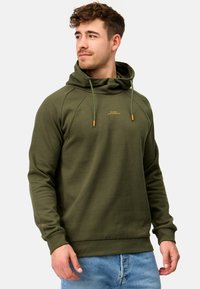 Sudadera de color verde oliva con cordón, mangas raglán y puños de canalé. Presenta texto bordado en dorado en el pecho y una tela suave y texturizada.