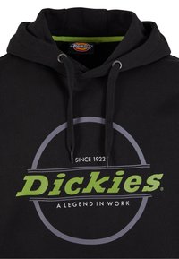 Svart hettegenser med en grønn logo som leser "Dickies" og "A Legend in Work," med et grått sirkulært design og snorhett.