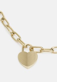 Gold chain bracelet with a heart-shaped pendant. Pendant features ribbed texture, and chain links are smooth and shiny.