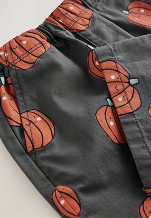 Tissu gris foncé avec un motif de citrouilles oranges répétées, d'une texture douce et d'une taille élastique.