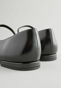 Czarne skórzane buty o połyskującym wykończeniu, zaokrąglonym tylnym designie, niskim obcasie i cienkich paskach na kostkę. Gładka faktura bez widocznych wzorów.