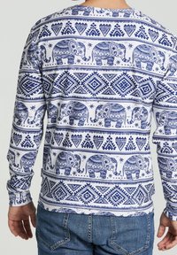 Wit shirt met lange mouwen, voorzien van blauwe olifantenpatronen en geometrische ontwerpen. Heeft een ronde halslijn en aansluitende mouwen.