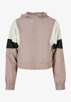 Kurtāka vējjakas versija gaiši rozā krāsā ar melnbaltiem krāsu bloku piedurknēm. Iekļauj priekšējo rāvējslēdzēju un kapuci ar aukliņu. Mīksta tekstūra.